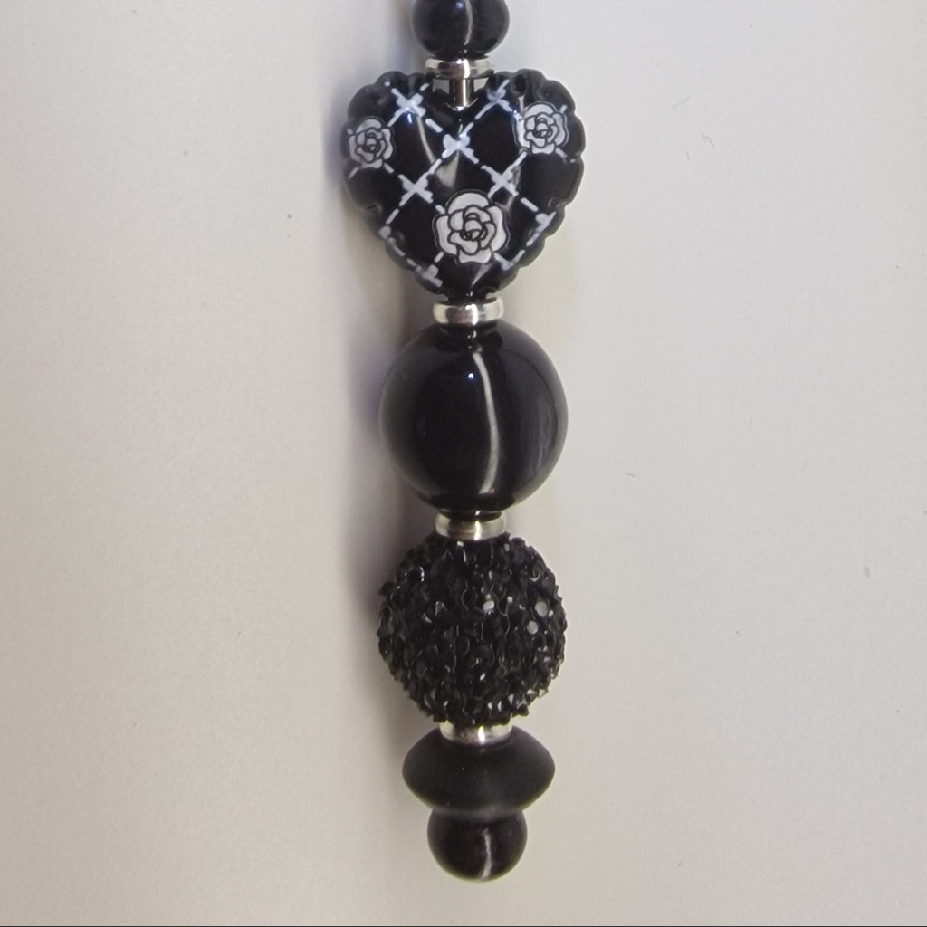 Handversierde zwarte sleutelhanger met hartje en zilverkleurige strass details – detailfoto