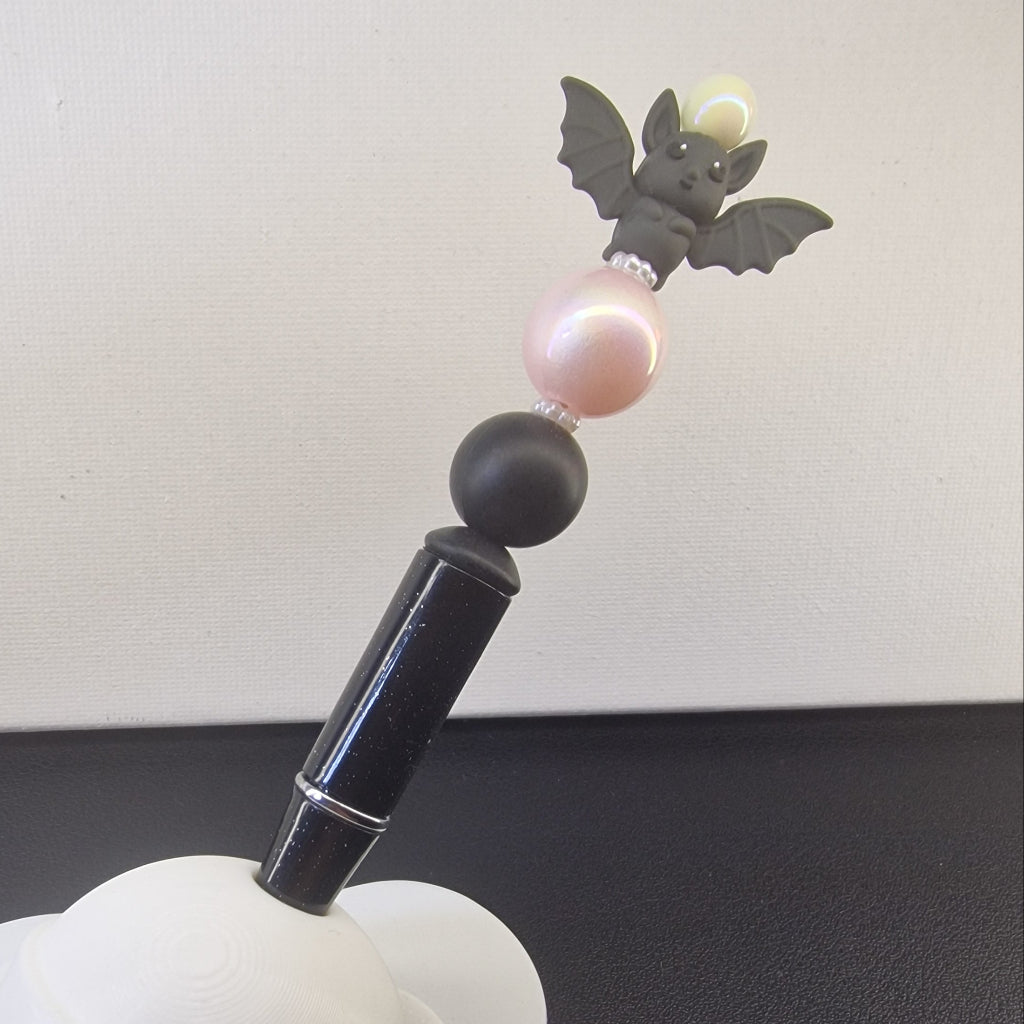 Handversierde zwarte gespikkelde pen met vleermuisje en roze kraal en zwarte kraal