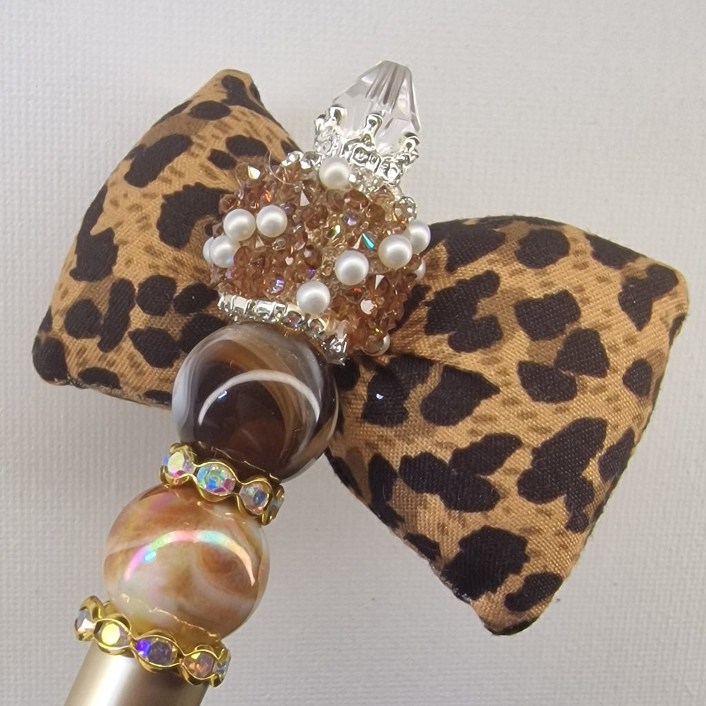 Handversierde goudkleurige pen met zachte strik in panter motief en strass kralen – detailfoto
