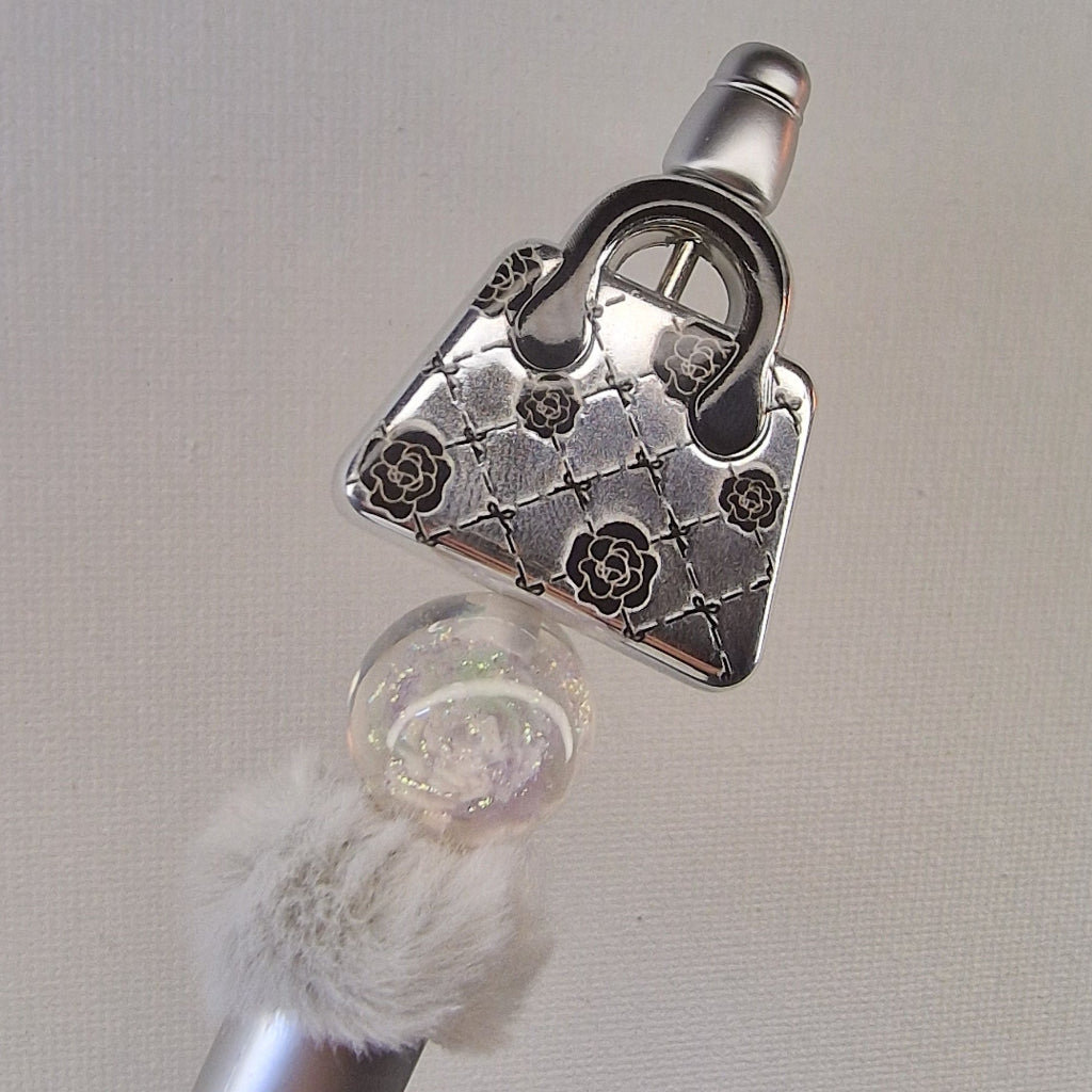 Handversierde zilveren pen met nepbont en zilveren handtasje met bloemetjes – detailfoto
