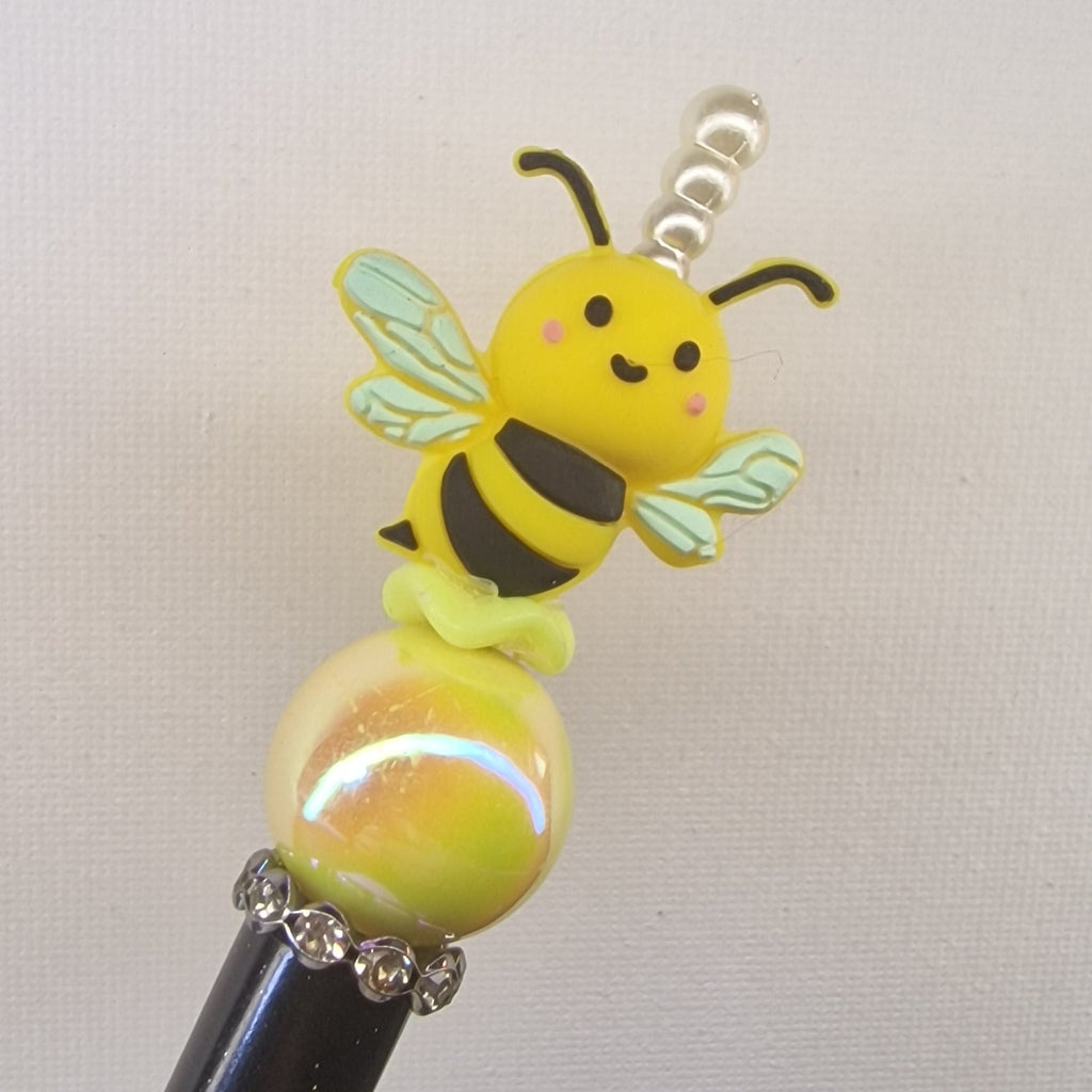 Handversierde zwarte gespikkelde pen met honingbijtje en gele kraal – detailfoto
