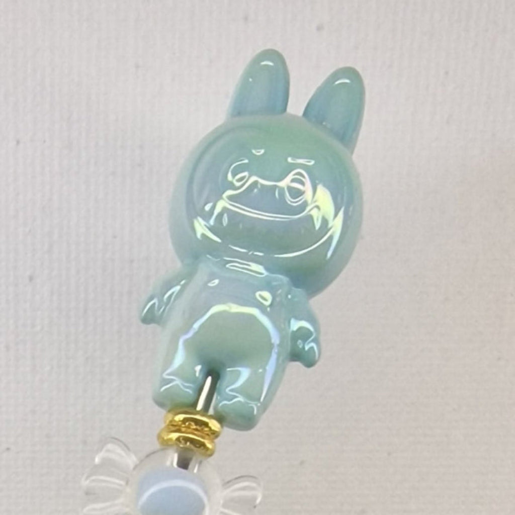 Handversierde turquoise fluffy pen met ondeugend poppetje en blauwe strass kralen – detailfoto
