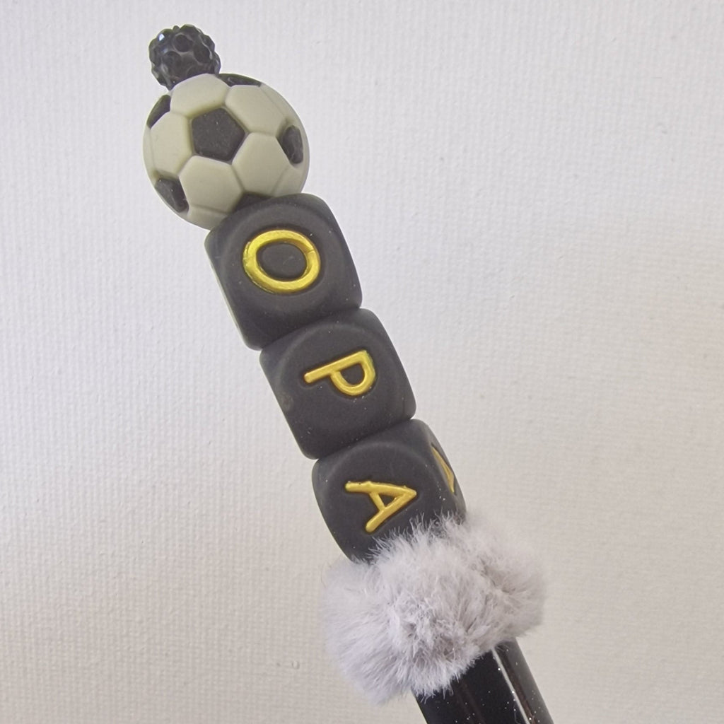 Handversierde zwarte pen met gouden letterkubussen 'opa', grijs nepbont en voetbal – detailfoto
