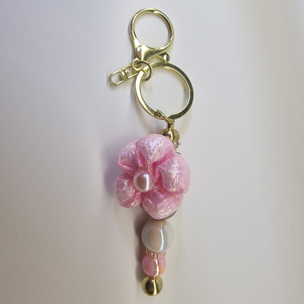 Handversierde goudkleurige sleutelhanger met roze bloem en parelmoer kralen
