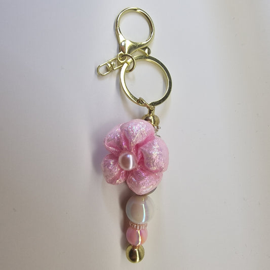 Handversierde goudkleurige sleutelhanger met roze bloem en parelmoer kralen
