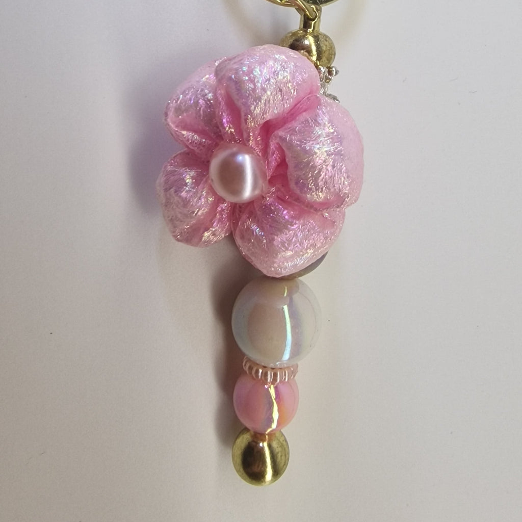 Handversierde goudkleurige sleutelhanger met roze bloem en parelmoer kralen – detailfoto
