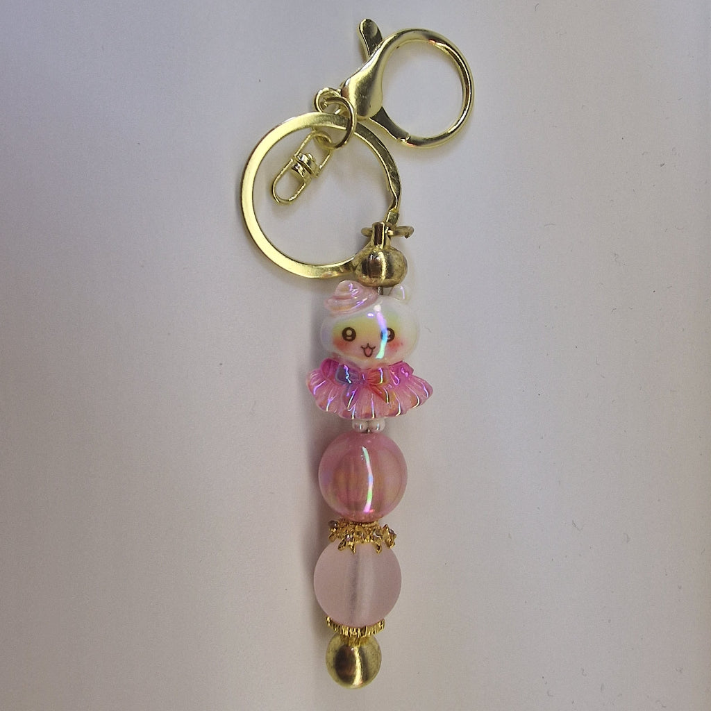 Handversierde goudkleurige sleutelhanger met poesje in roze rokje en terracotta kralen
