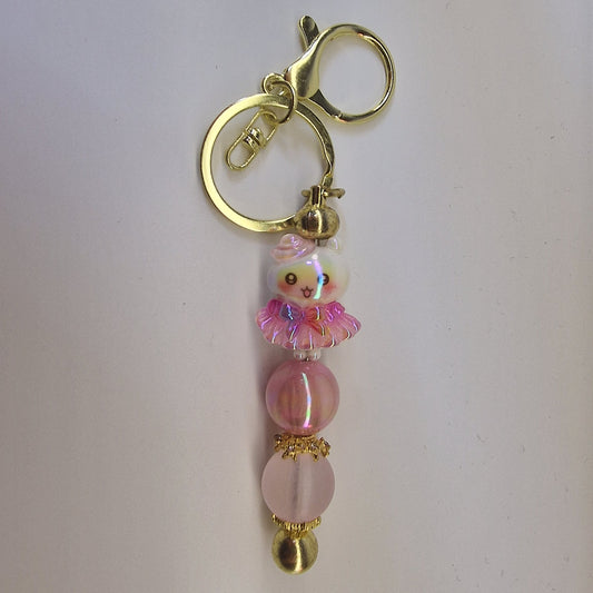 Handversierde goudkleurige sleutelhanger met poesje in roze rokje en terracotta kralen
