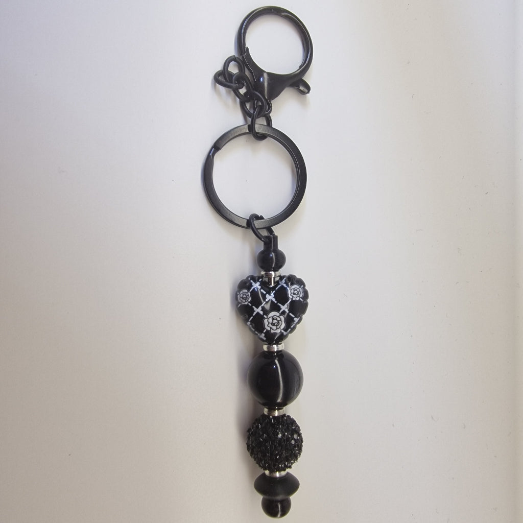 Handversierde zwarte sleutelhanger met hartje en zilverkleurige strass details
