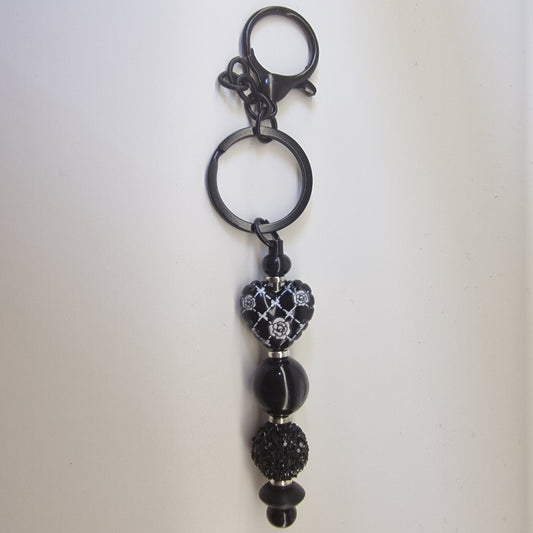 Handversierde zwarte sleutelhanger met hartje en zilverkleurige strass details
