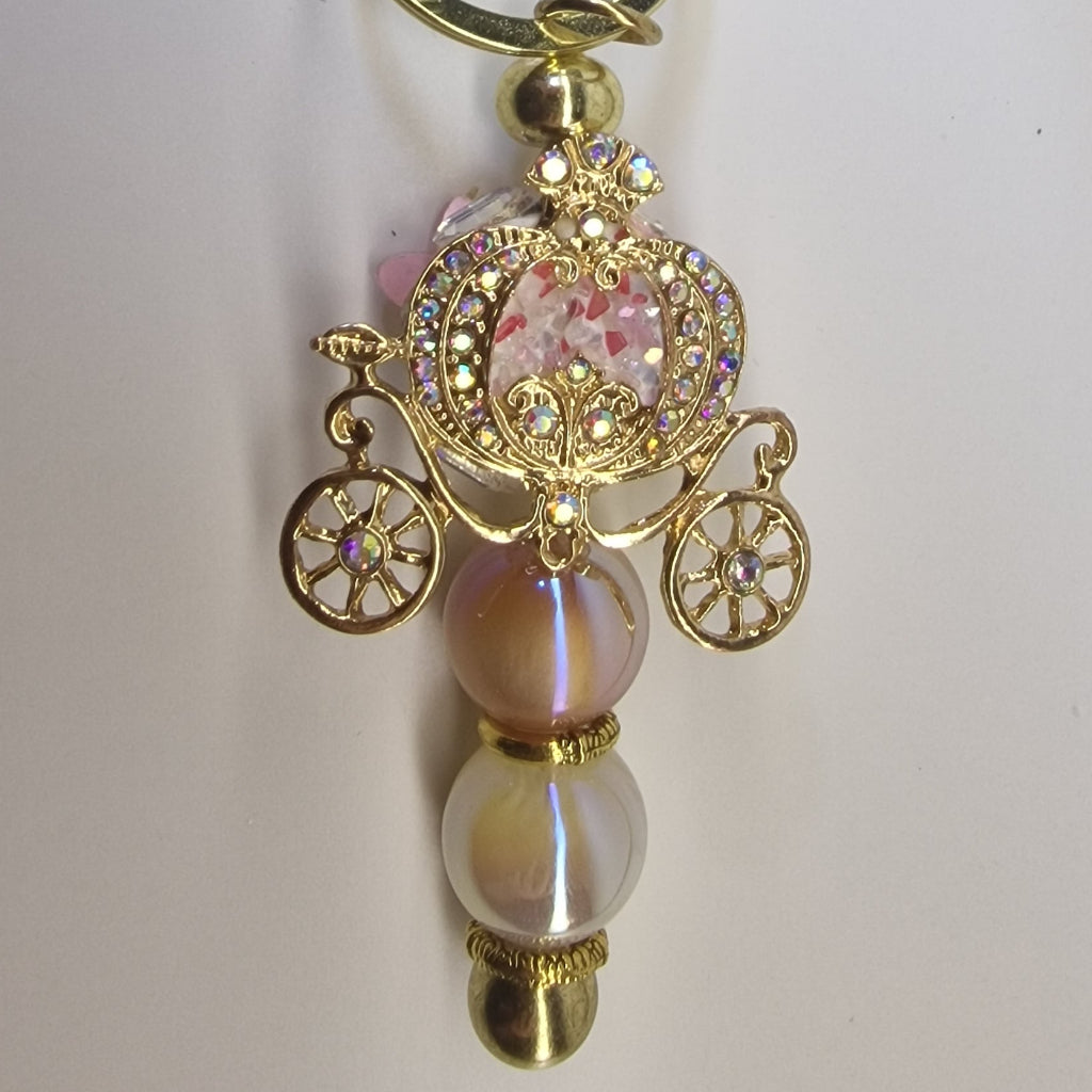 Handversierde goudkleurige sleutelhanger met koets en strass-steentjes – detailfoto